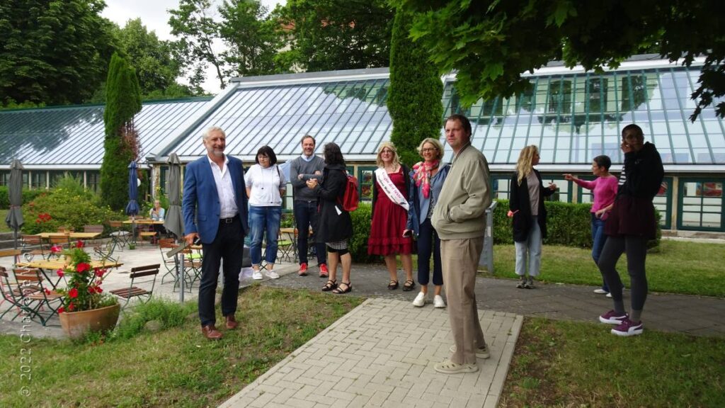 Kulturakteure aus Saale-Orla und dem Hildesheimer Land unterhalten sich in einem Garten.