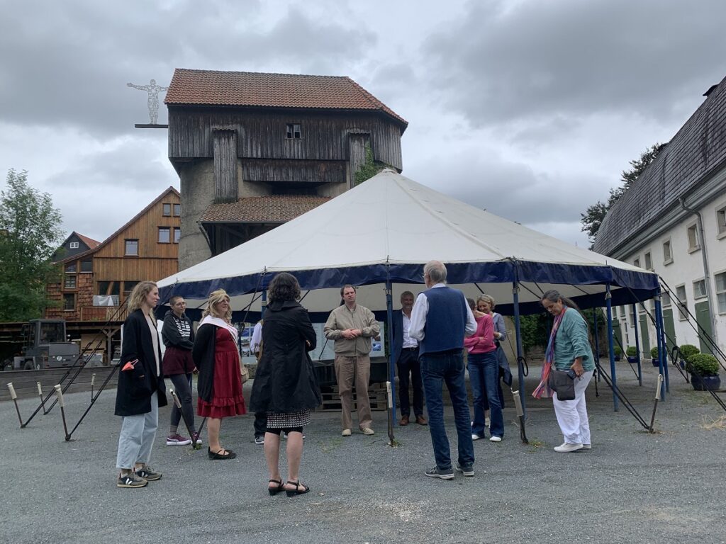 Kulturakteure aus Saale-Orla und dem Hildesheimer Land unterhalten sich auf einem Dorfplatz.