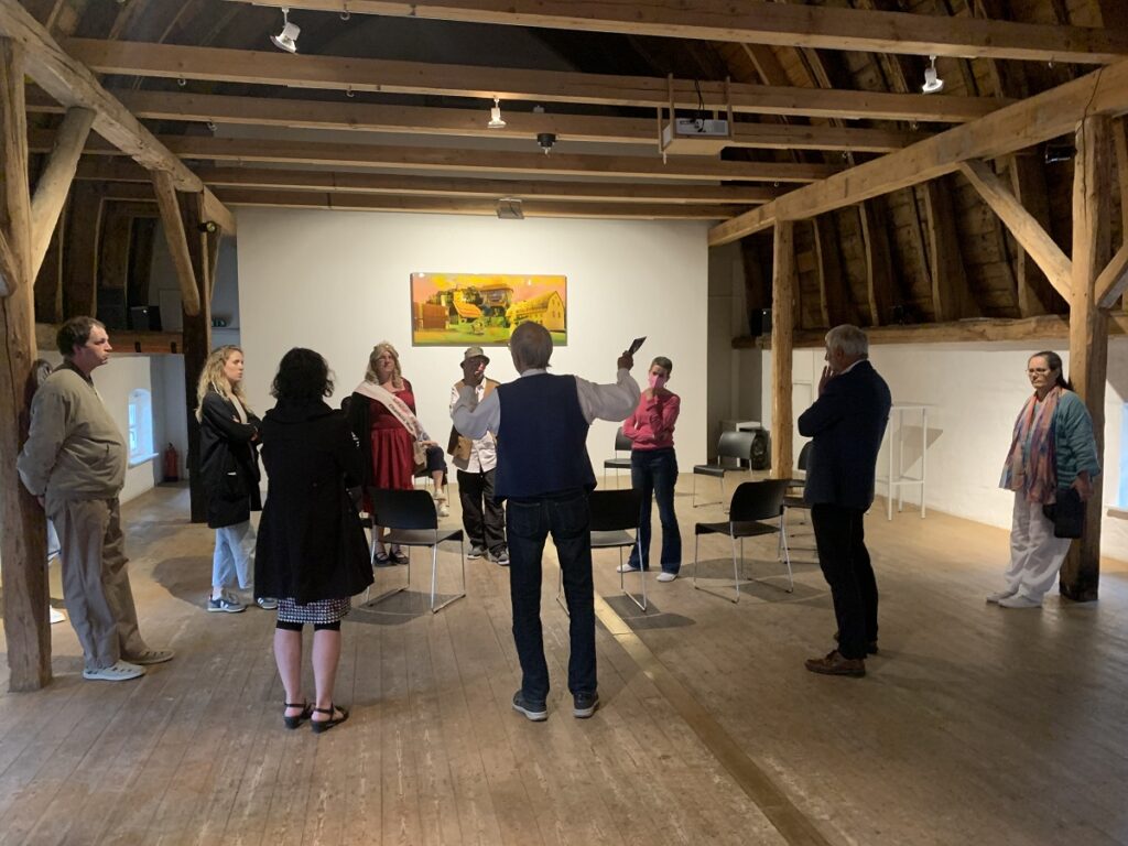 Kulturakteure reden miteinander in einem großen Raum mit Holzbalken und Gemälden.
